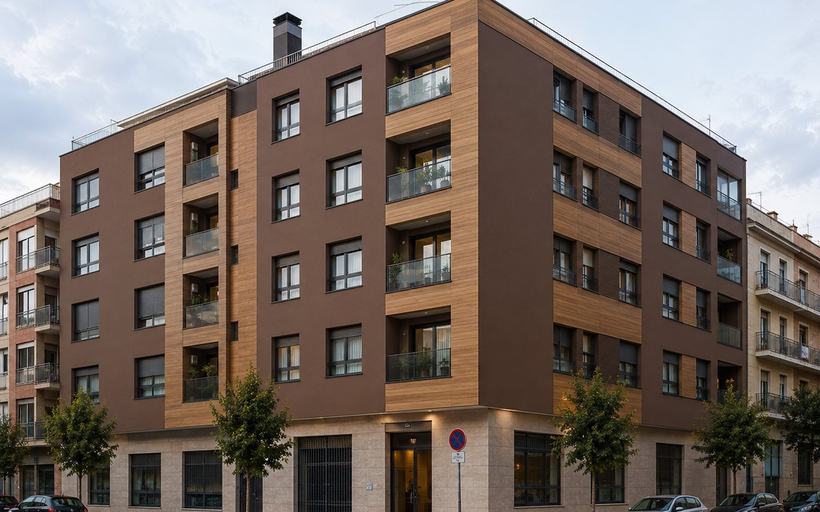 Edificio de viviendas de cinco alturas en esquina con fachada de acabado continuo en tono tierra, paños verticales de acabado madera en las terrazas y planta baja comercial con zócalo aplacado.